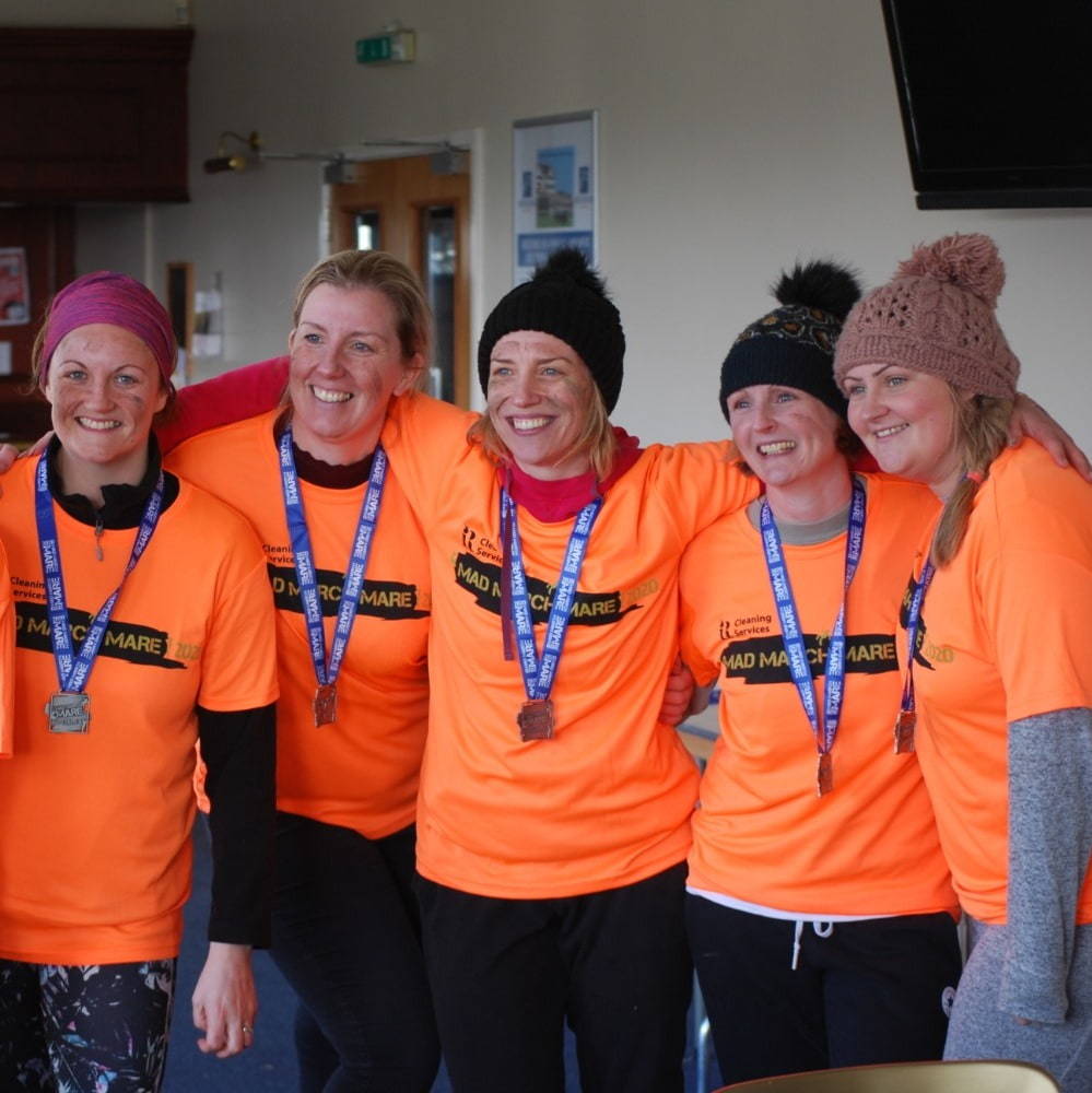 a team of women wearing medals for taking part in charity event