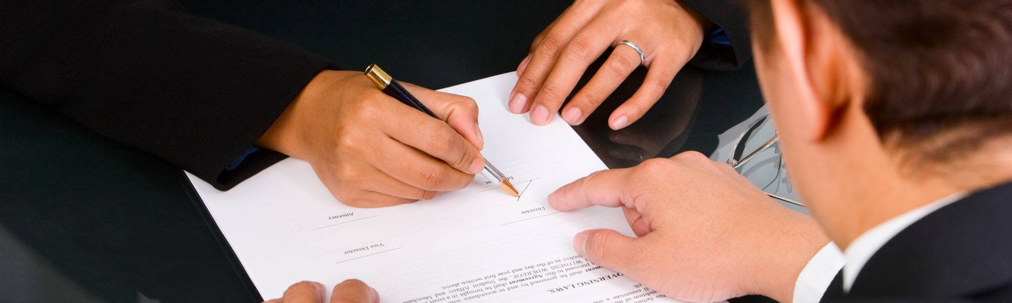 close up of two people signing a document