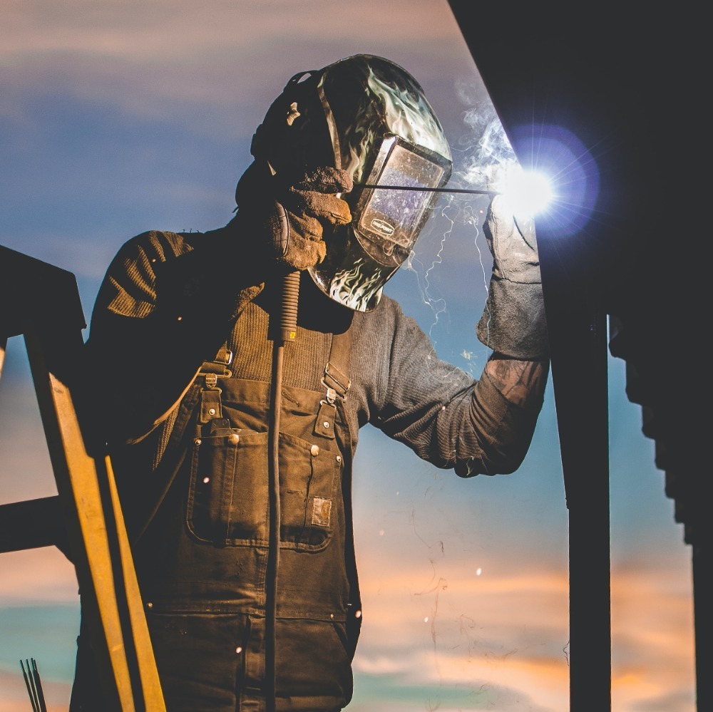 person welding, equipped with PPE