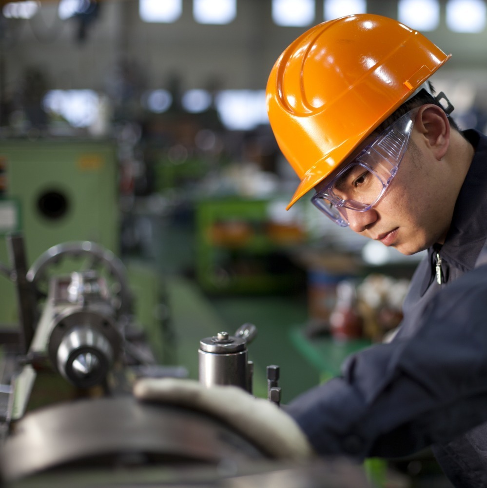 man with an orange hard hat looking at equipment