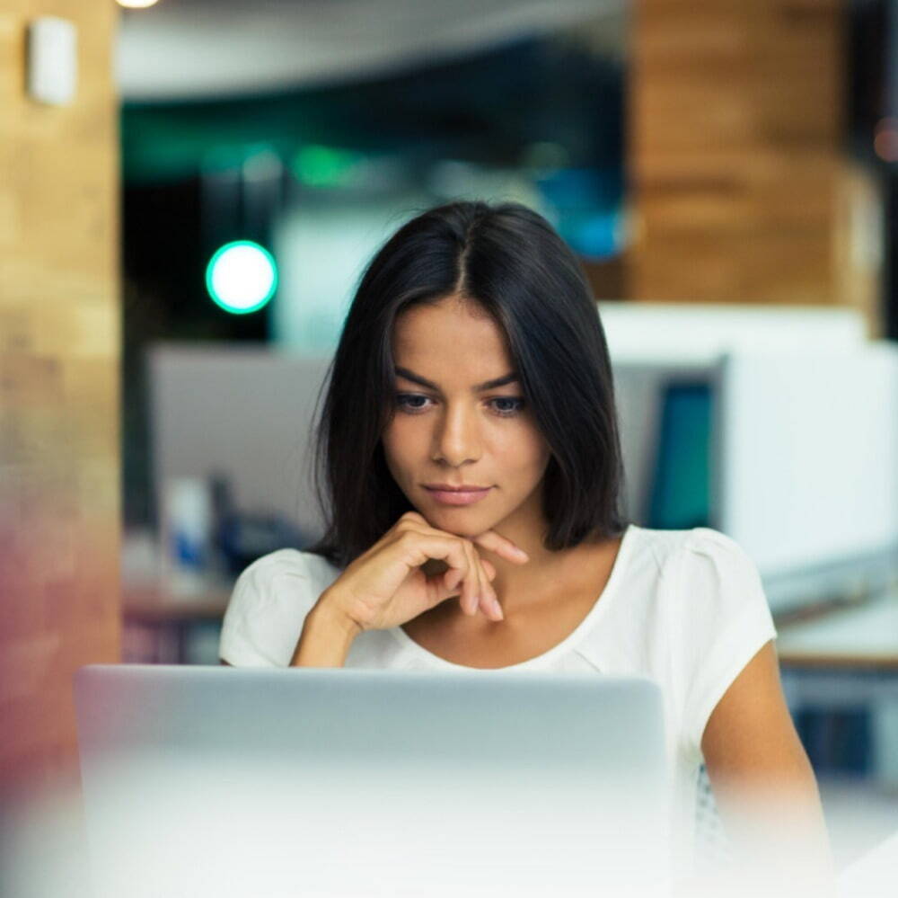 lady looking at her laptop resting her head on her hand