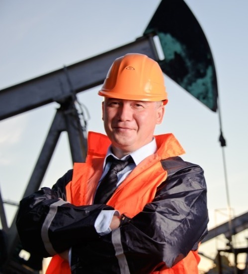 a man crossing his arms and smiling wearing an orange hard hat