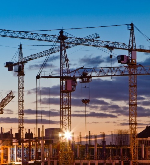 image of 3 large cranes at dusk