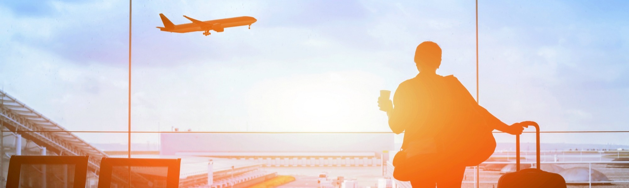 Woman looking out of a large window at an aeroplane