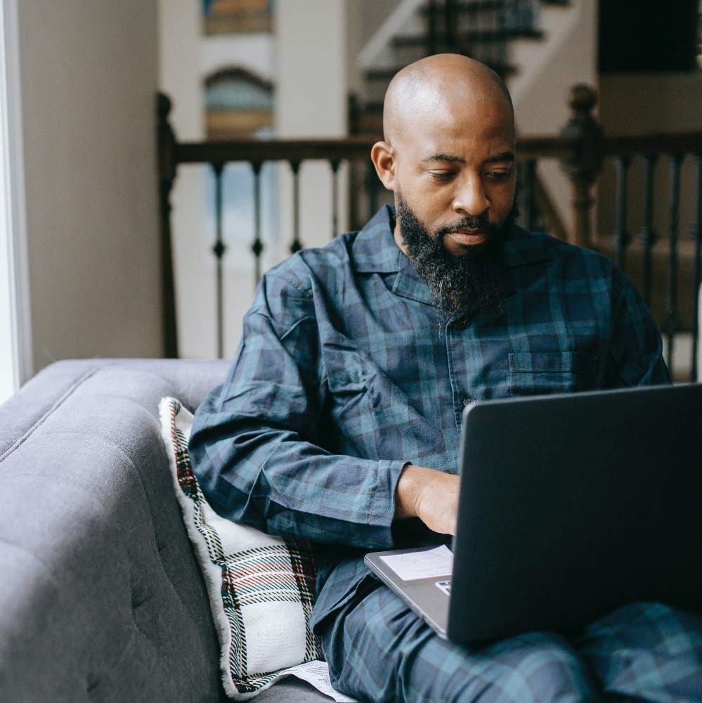 man sat on a sofa using his laptop