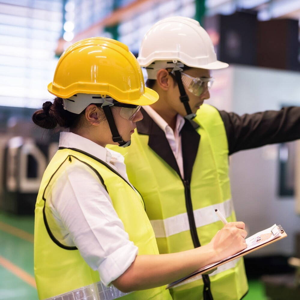 a young woman and man in high-vis vests and hard hats