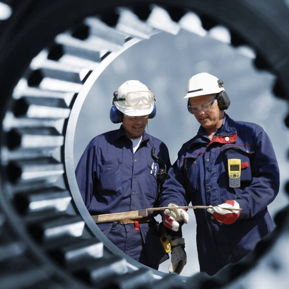 2 men with hard hats being viewed through a pipe