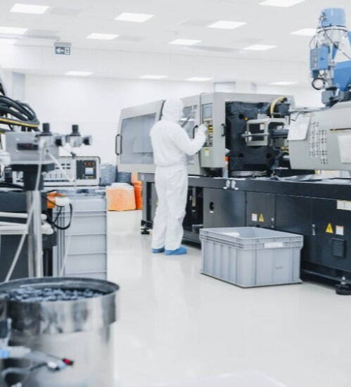 person in white PPE in a clinical environment looking at a large machine 