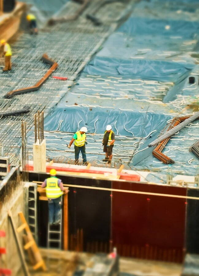 3 mean in safety gear stood on top of a building being constructed